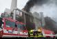 PHA_Požár ve spalovně v Malešicích-pohled na hasičskou techniku, a zasahující hasiče na žebříku a jejich kolegy před vozy
