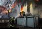 PHA_Požár haly v pražském Braníku_4 hasiči při zásahu, 2 stojí před hořící halou na komunikaci, 2 na přilehlém přístřešku 