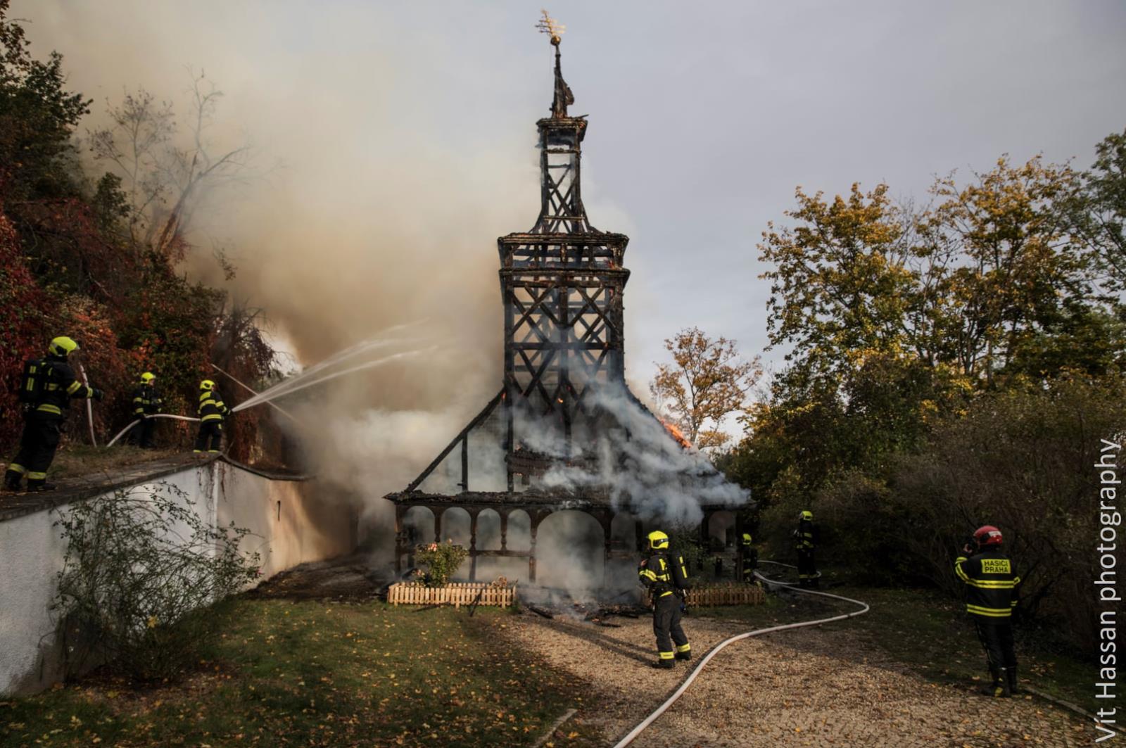 PHA_Požár kostela sv. Michaela_celkový pohled na ohořelý kostel a hasiče, kteří u požáru zasahují.jpg