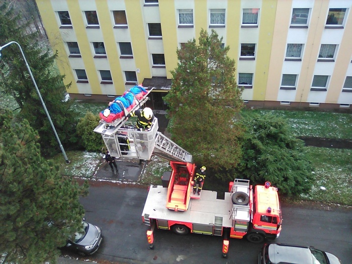 MSK_záchrana zraněného muže ze střechy panelového domu v Ostravě_hasič plošině zajištuje muže ležícího na nosítkách.jpg