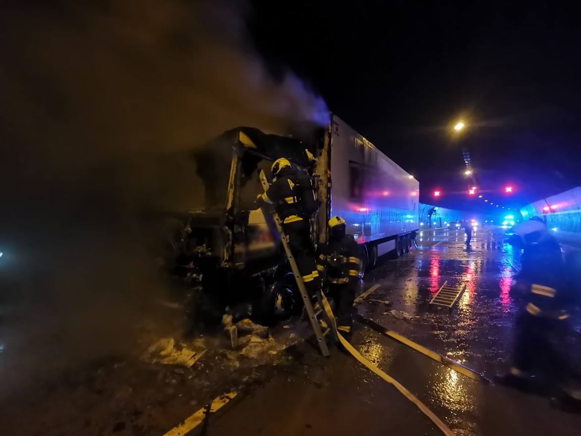 PHA_Požár kamionu v Lochkovském tunelu v Praze_hasič na žebříku nastaveném ke kabině kamionu dohašuje požár.jpg