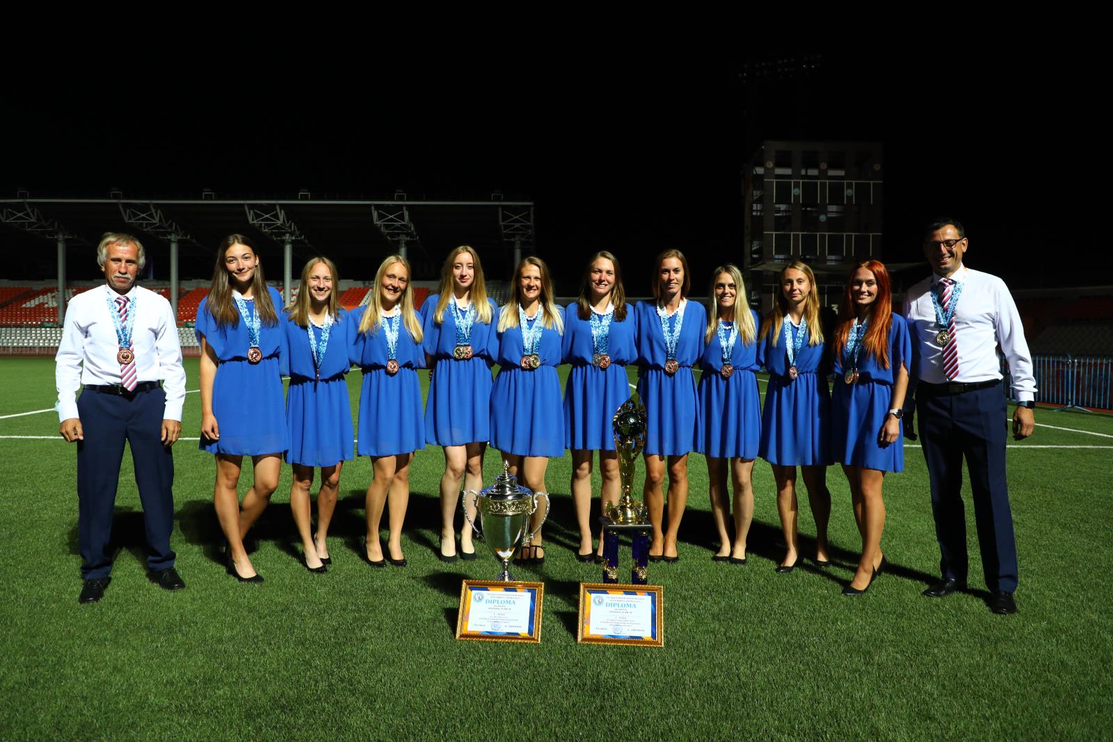 Společná fotografie českého týmu žen při závěrečném ceremoniálu ve slavnostním oděvu a cenami.jpg