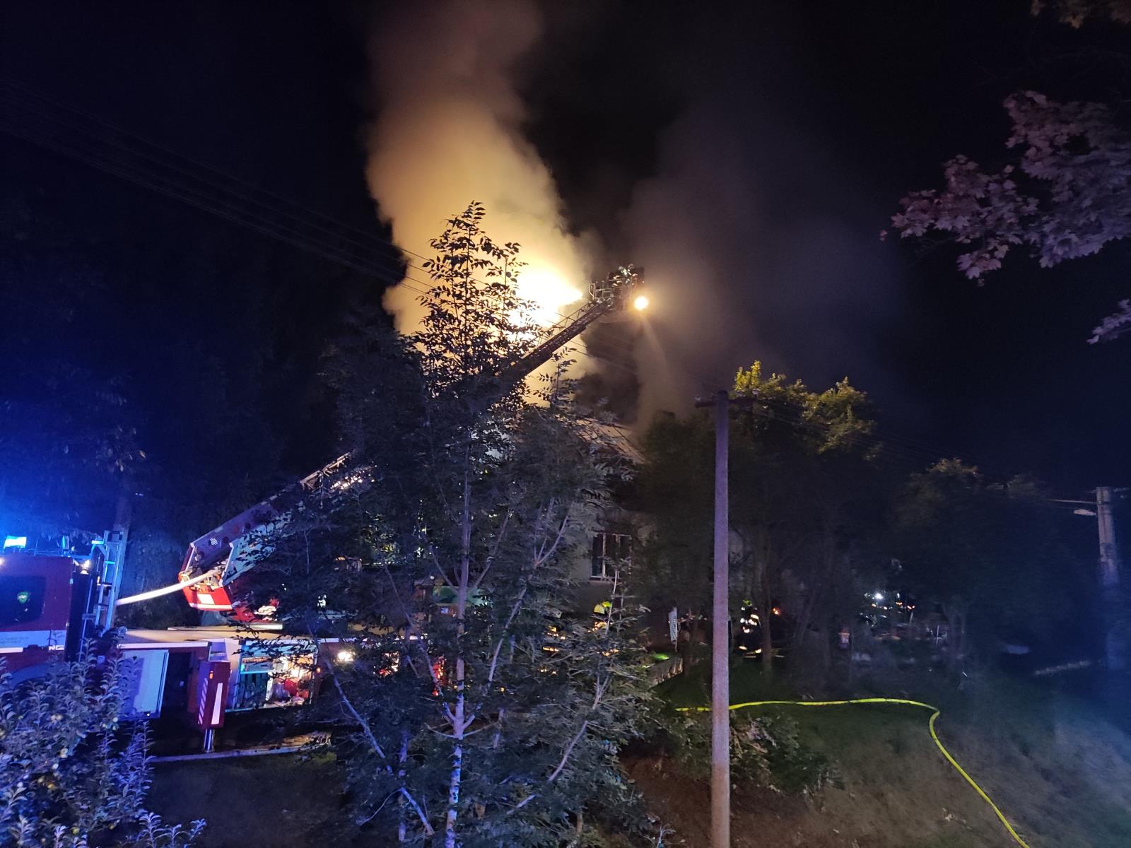 LIK_hasiči likvidují požár RD v Bozkově_pohled na hořící objekt a hasiče zasahující z plošiny.jpg