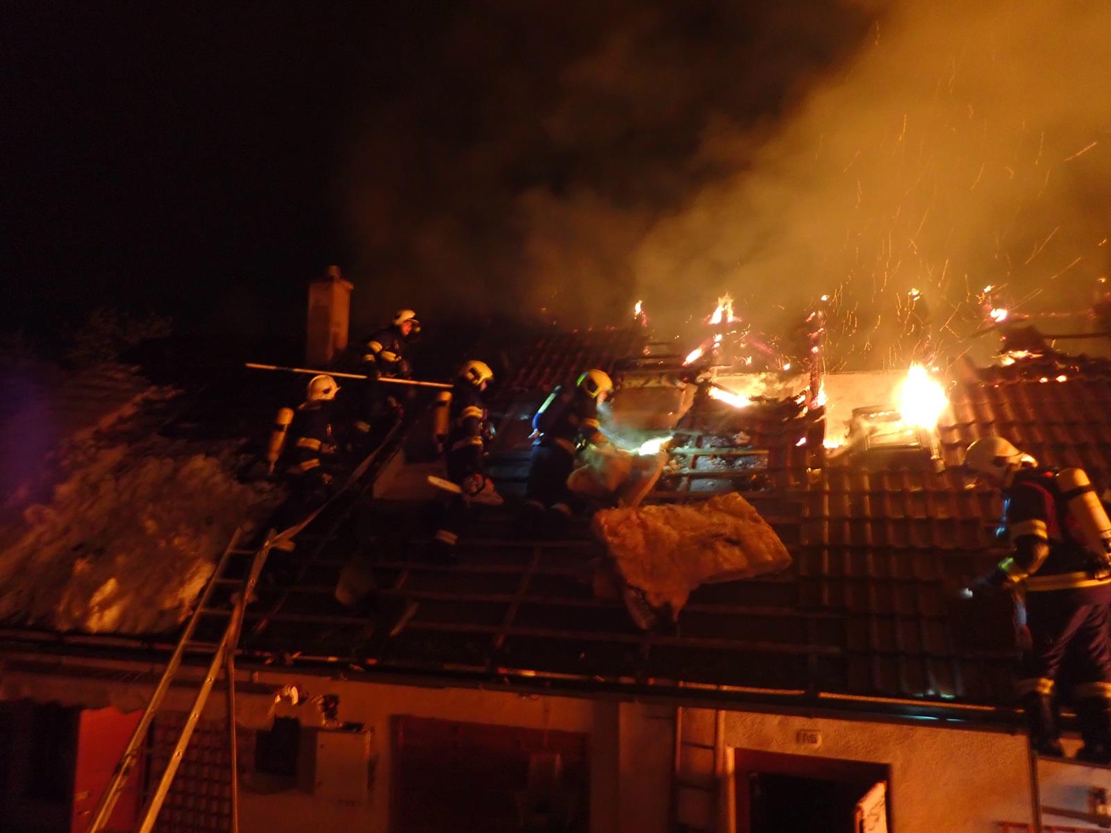 ZLK_Požár hospodářské budovy ve Vizovicích_plameny zasažená střecha a zasahující hasiči na ní.jpg