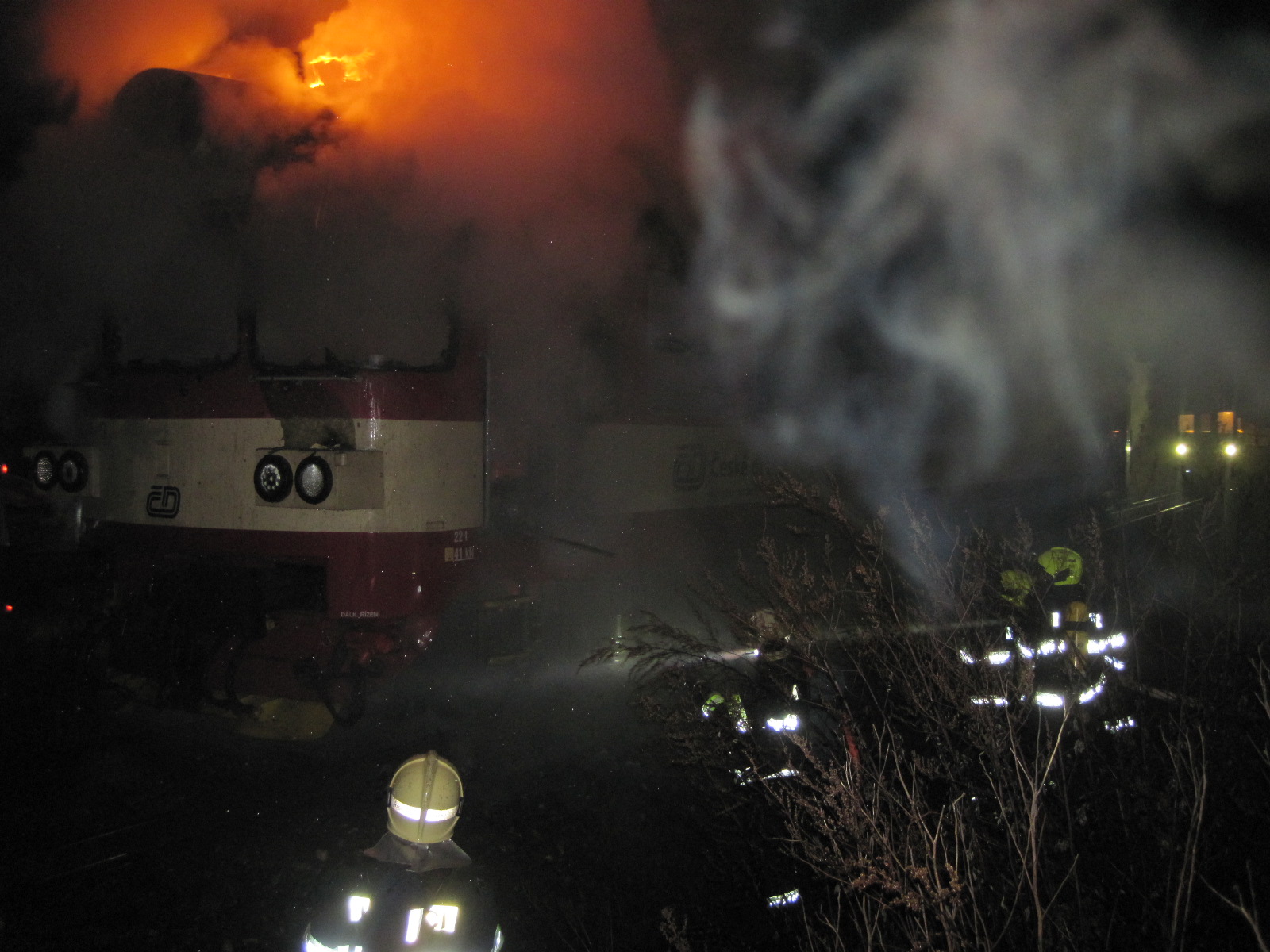 ZLK_Při jízdě vlaku začala hořet kabina strojvedoucího_hasiči před hořícím vozem.jpg