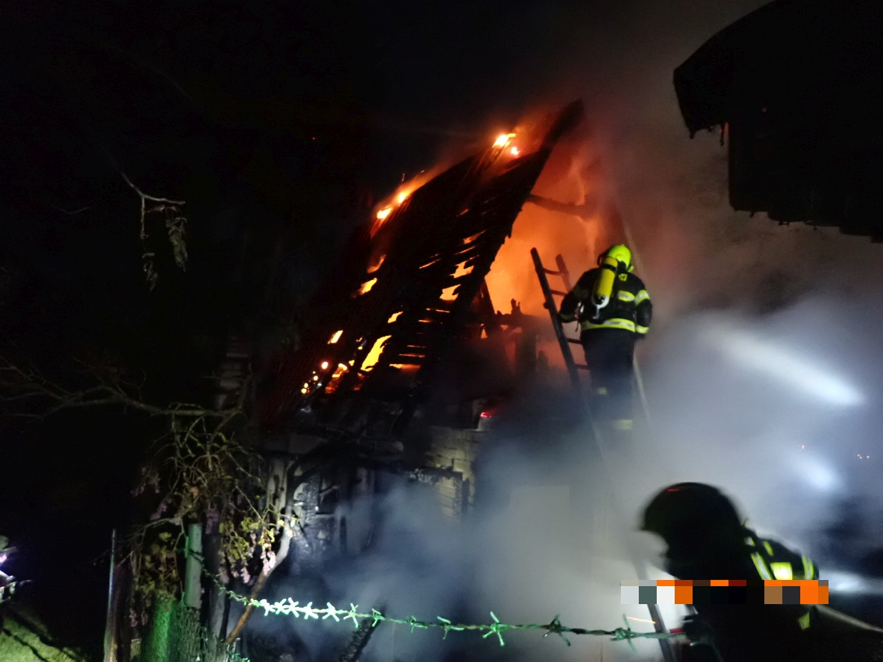 ZLK_Požár chatky v Uherském Brodě_Hasič leze po žebříku do hořícího objektu.jpg