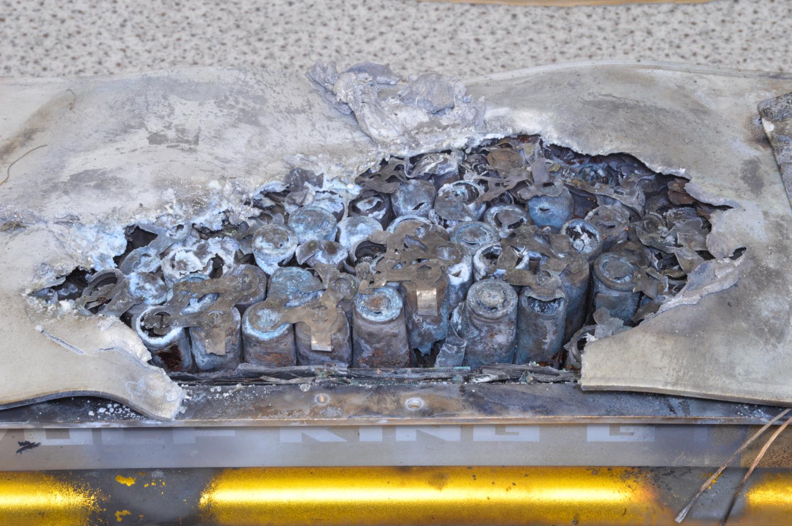 Detail úložiště akumulátoru s vyhořelými články a roztaveného plechového krytu elektrické koloběžky
