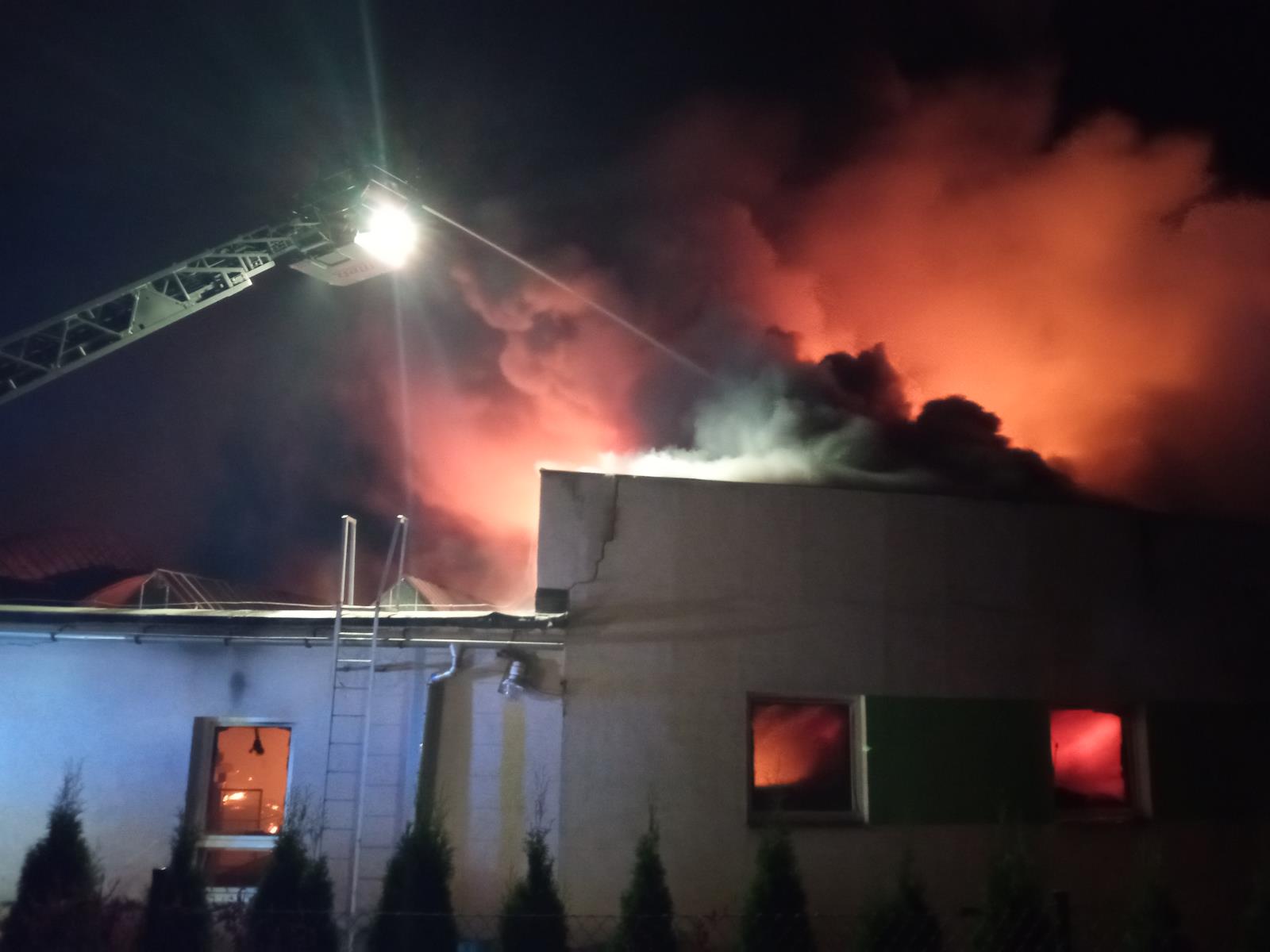 LIK_Požár průmyslového objektu v Roztokách u Jilemnice_hasičí z žebříku hasí hořící objekt.jpg