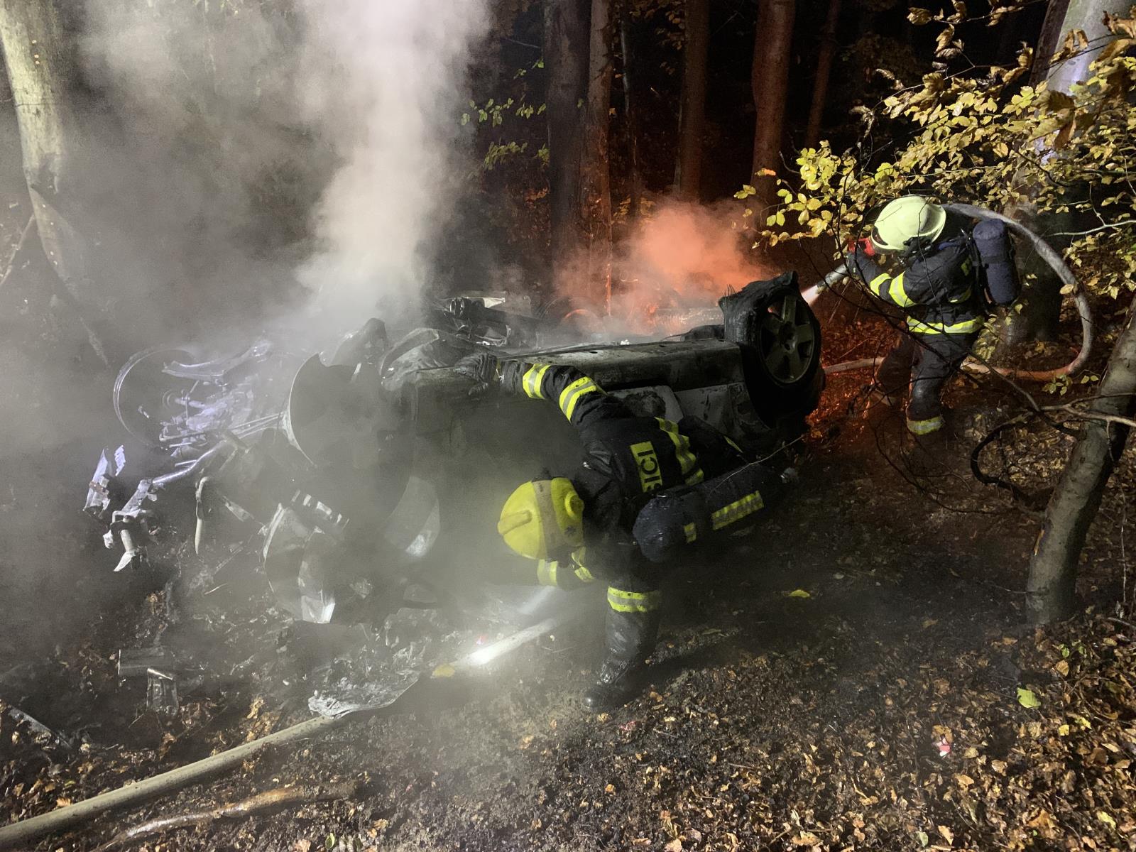 ZLK_DN s tragickými následky_2 hasiči hasí hořící osobní automobil, který spadl ze srázu do lesa.jpg