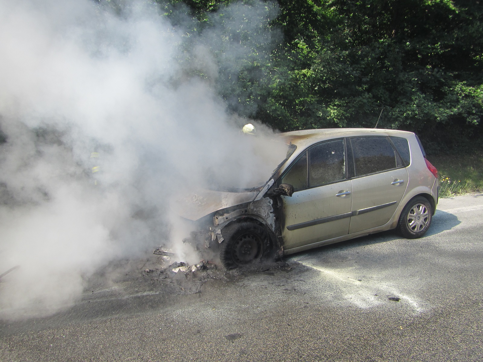 Pohled na požárem poškozený automobil a kouř z motorového prostoru