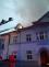 ze střechy se valí dým, hasiči hasí požár za pomoci vodního proudu z výškové techniky
