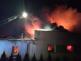 LIK_Požár průmyslového objektu v Roztokách u Jilemnice_hasičí z žebříku hasí hořící objekt