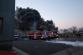 SČK_Požár mrazíren v Mochově_z budovy stoupá hustý černý kouř, před ní stojí hasičská technika a hasiči, kteří zasahují