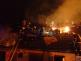 ZLK_Požár hospodářské budovy ve Vizovicích_plameny zasažená střecha a zasahující hasiči na ní
