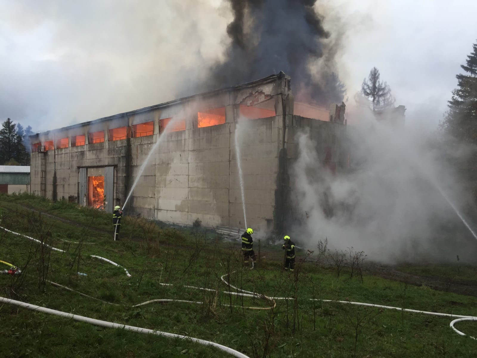 KHK_Požár haly se senem v Bartošovicích_3 hasiči hasi vodními proudy hořící halu.jpg