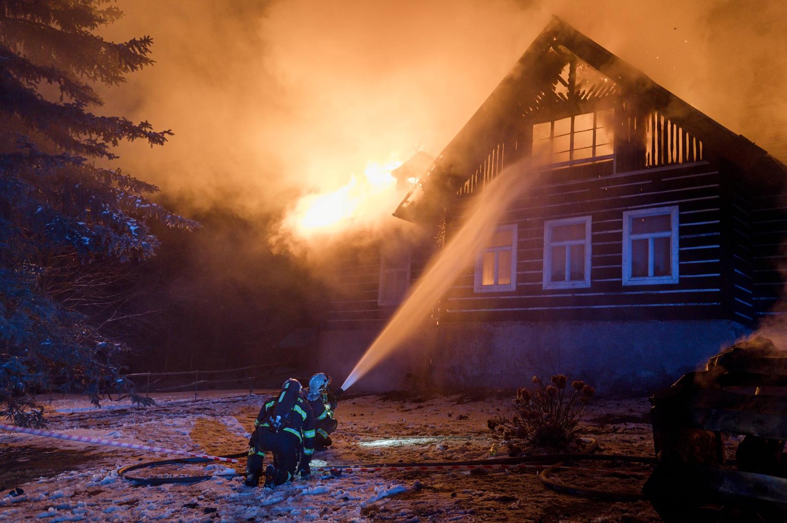 LIK_požár domu ve Světlé pod Ještědem_pohled na hasiče, kteří 1 proudem hasí hořící roubenku zespoda.jpg