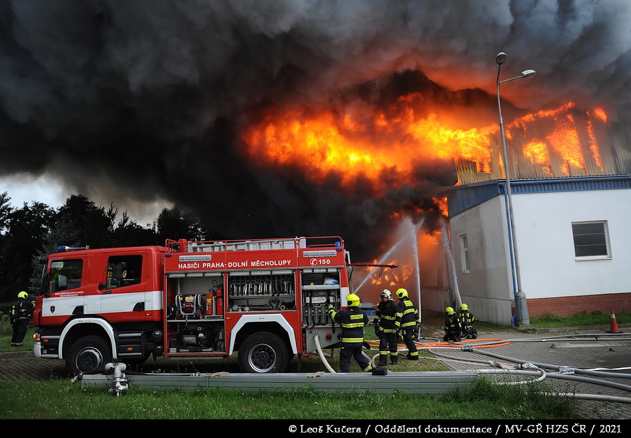 PHA_Požár haly v Uhříněvsi_pohled na cisternu, hasiče a hořící halu.JPG