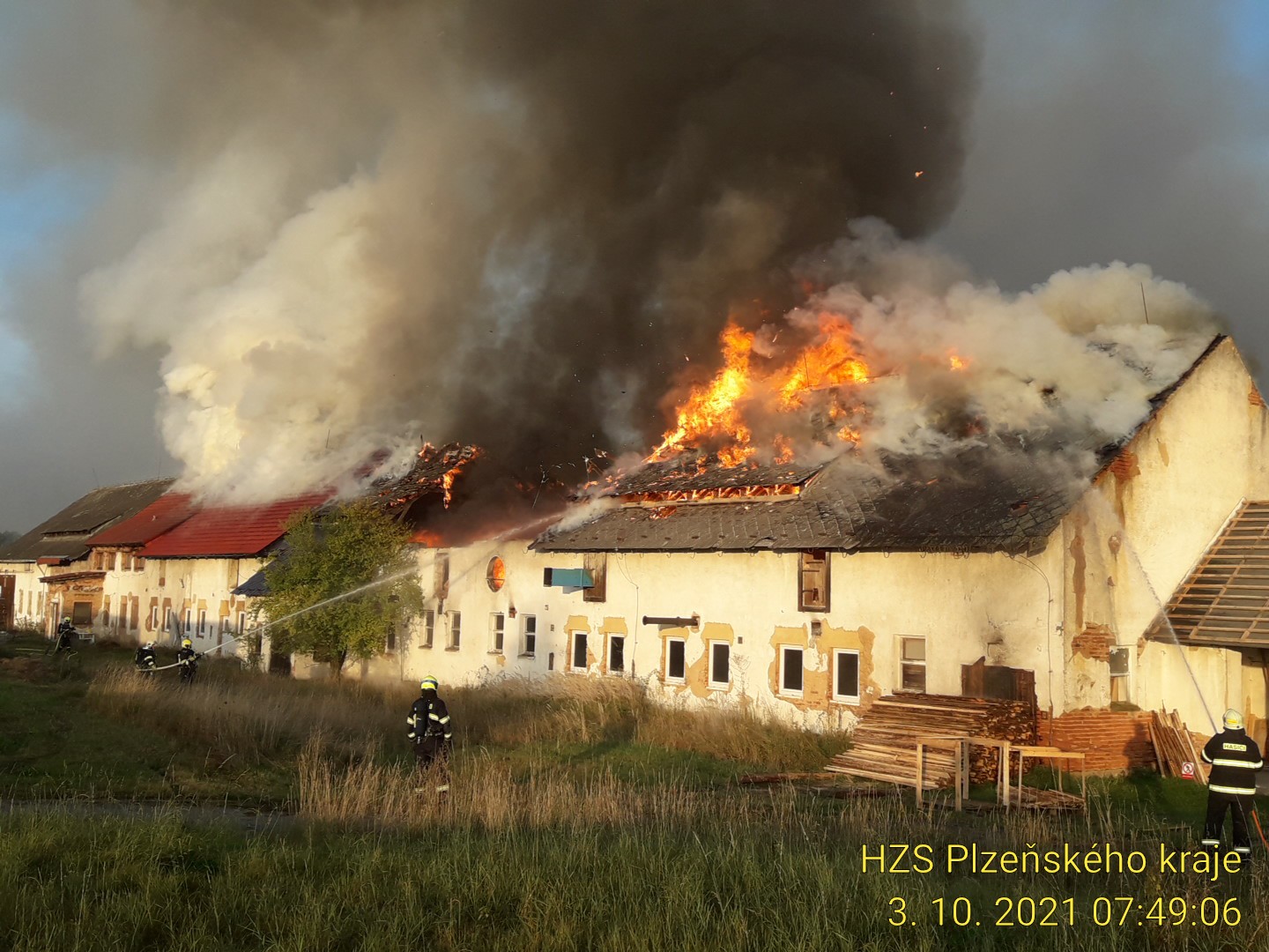 PLK_Požár objektu bývalého JZD_budova v plamenech a zasahující hasiči.jpg