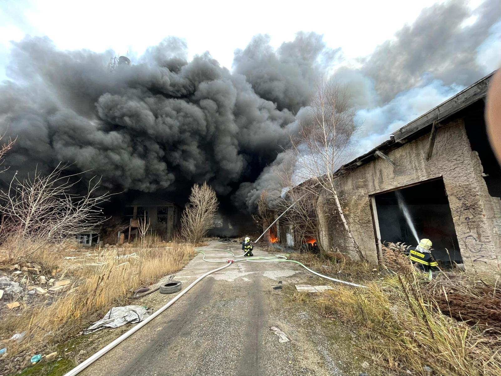SČK_Požár pneumatik v Kladně_zasahující hasiči před hořícím objektem.jpg