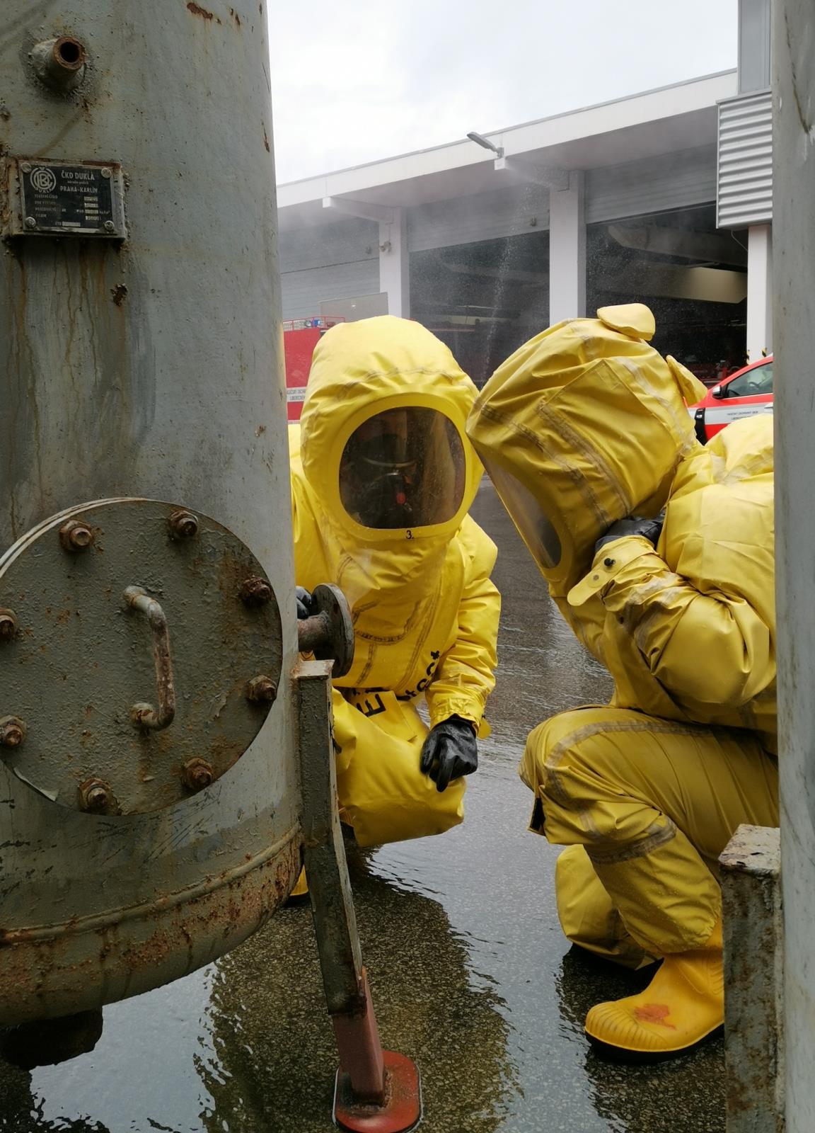 LIK_cvičení_záchrana osoby při úniku amoniaku_2 hasiči ve žlutých ochranných oděvech zkoumají ventil nádrže.jpg