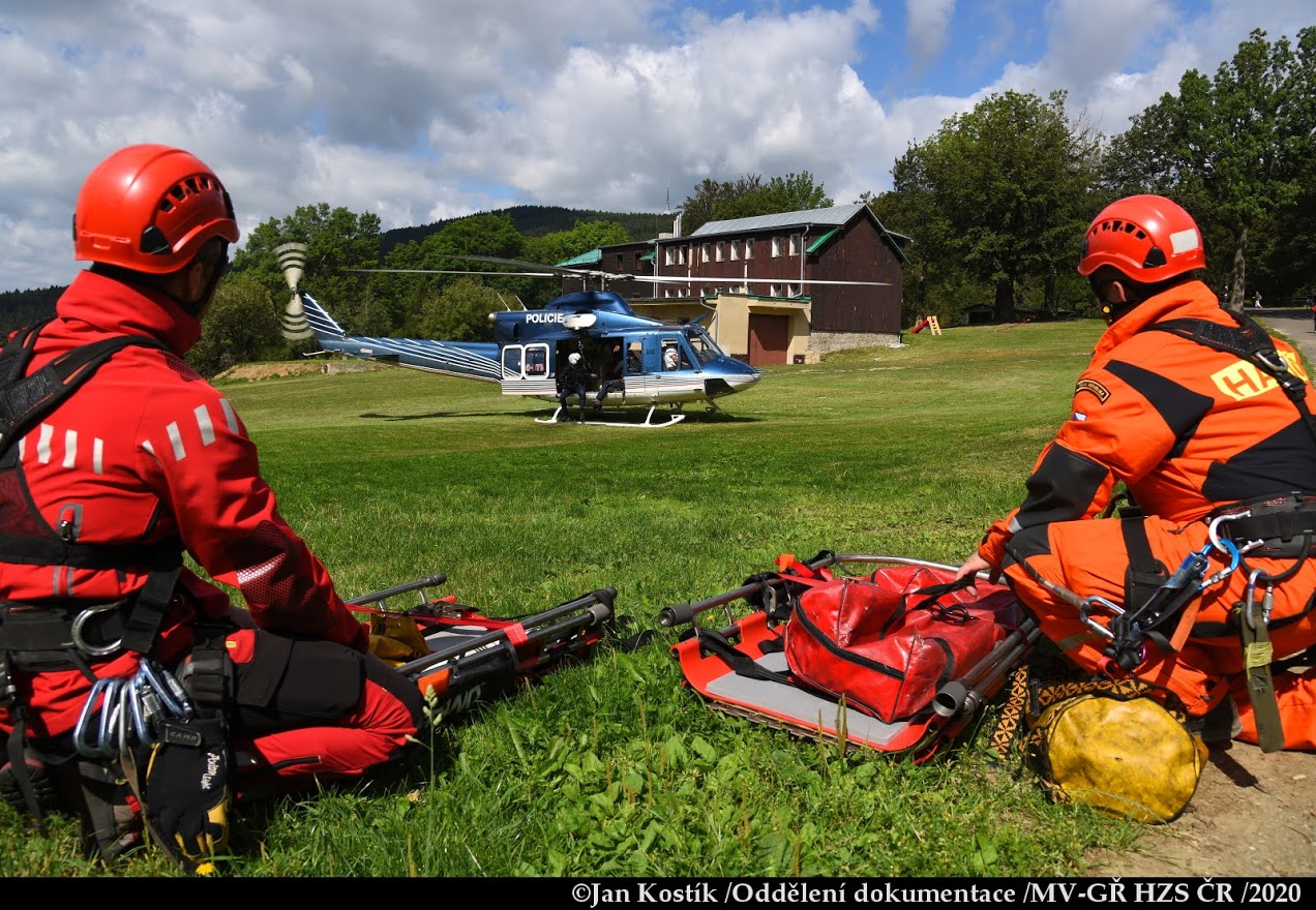 PHA_výcvik leteckých záchranářů_2 hasiči sledují na louce přistávající vrtulník.JPG