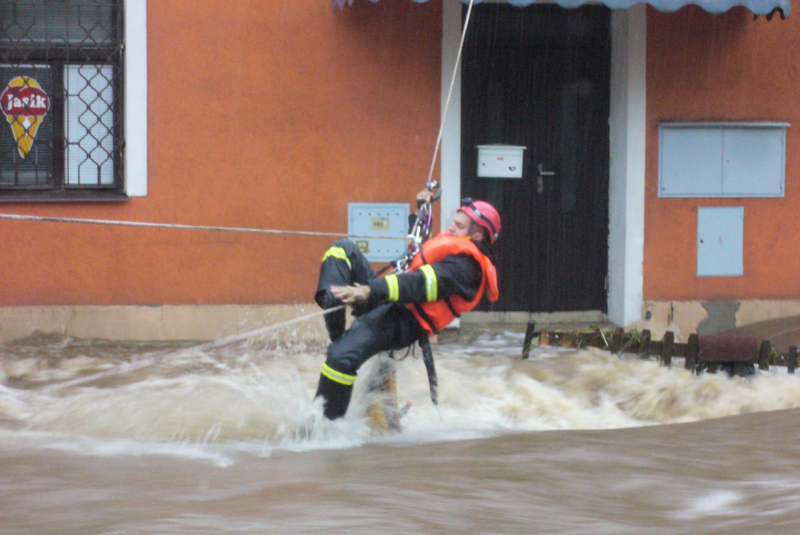 35_LIK_povodně Mníšek_hasič se na laně přesunuje přes zaplavenou ulici.JPG