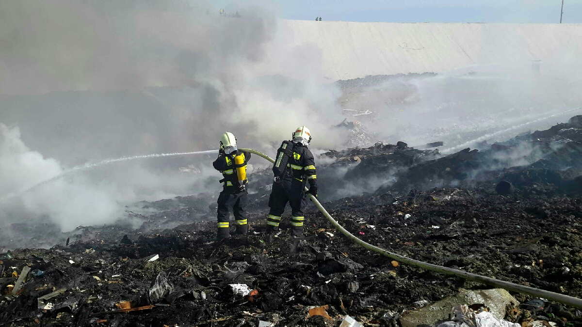 JMK_Požár skládky odpadu na Brněnsku_pohled na 2 hasiče kteří pomocí 1 proudu hasí odpad.jpg